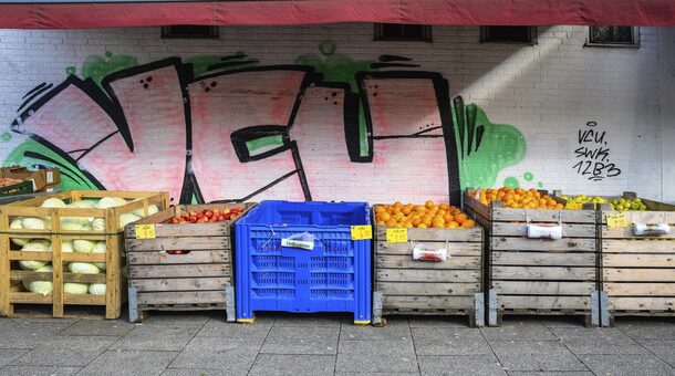 Unterschiedliches Obst in großen Boxen vor einer Wand, die mit Graffiti besprüht ist.