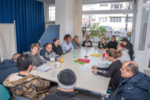 Gruppe von Menschen sitzt um Tisch herum