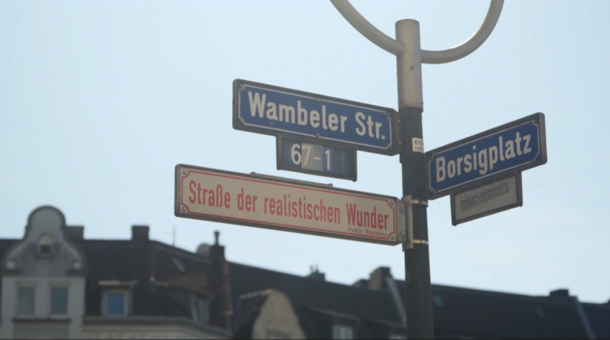 Straßenschild am Borsigplatz in Dortmund zeigt die Straßen "Wambeler Str." und "Borsigplatz" und das Zusatzschild "Straße der realistischen Wunder".