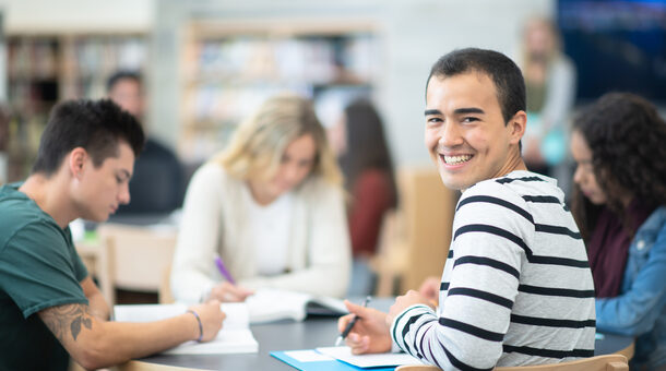 Male Student Smiling at a Table With His Peers stock photo