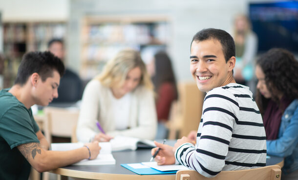 Male Student Smiling at a Table With His Peers stock photo