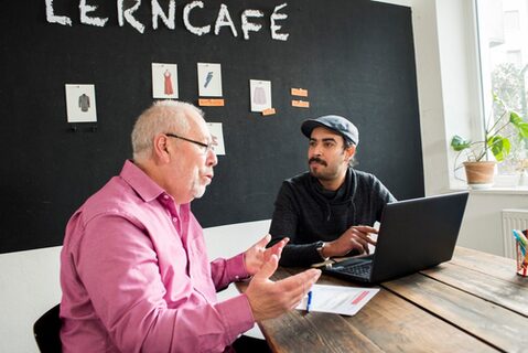 zwei Männer sitzen an einem Tisch und unterhalten sich