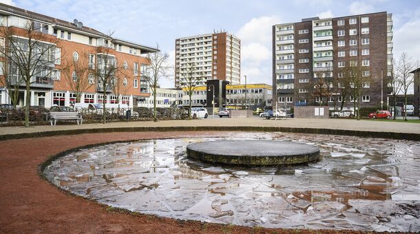 Ein Platz mit einem Brunnen im Vordergrund und Hochhäusern im Hintergrund.